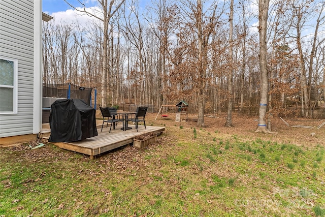 view of yard featuring outdoor dining area, a trampoline, and a deck