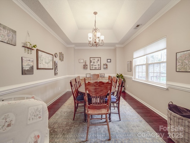 dining area featuring dark wood-style flooring, a raised ceiling, visible vents, and baseboards