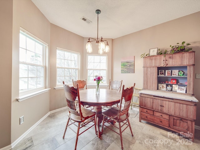 dining area featuring a chandelier, visible vents, a textured ceiling, and baseboards