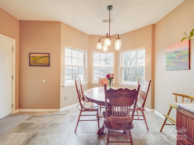 dining space featuring a chandelier, a textured ceiling, visible vents, and baseboards