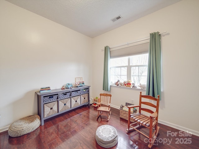 sitting room with dark wood-style flooring, visible vents, a textured ceiling, and baseboards