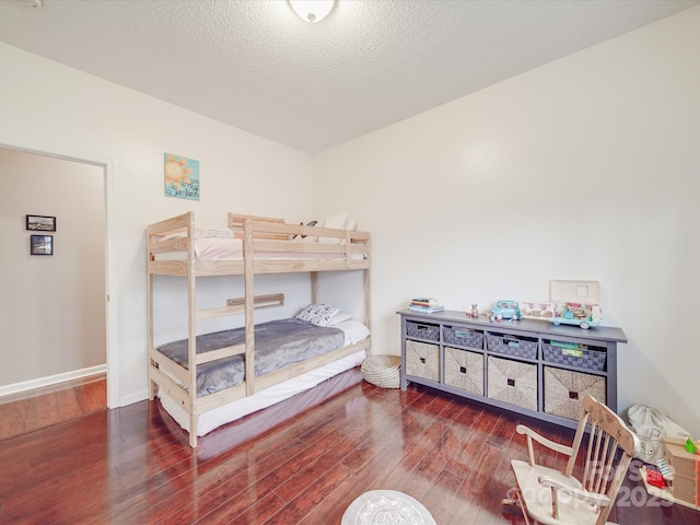 bedroom featuring dark wood-style floors, a textured ceiling, and baseboards