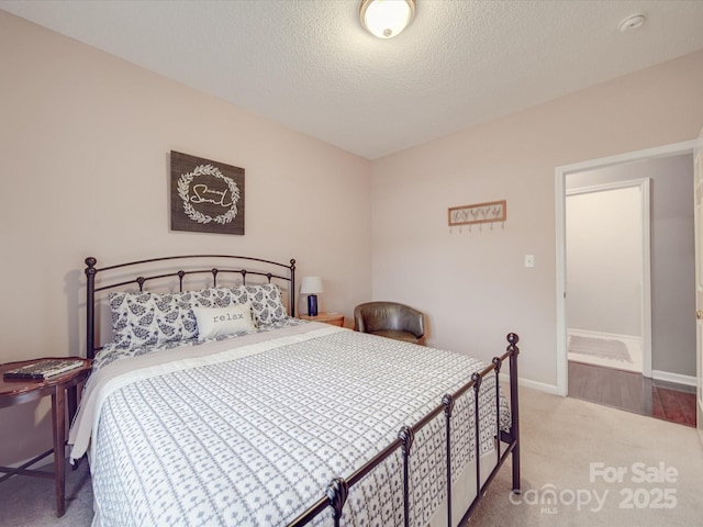 bedroom featuring baseboards, a textured ceiling, and light colored carpet