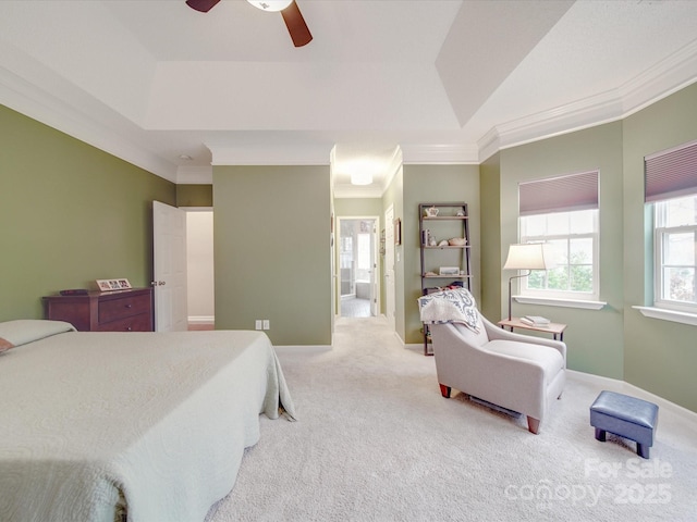 bedroom with a raised ceiling, light colored carpet, crown molding, and baseboards