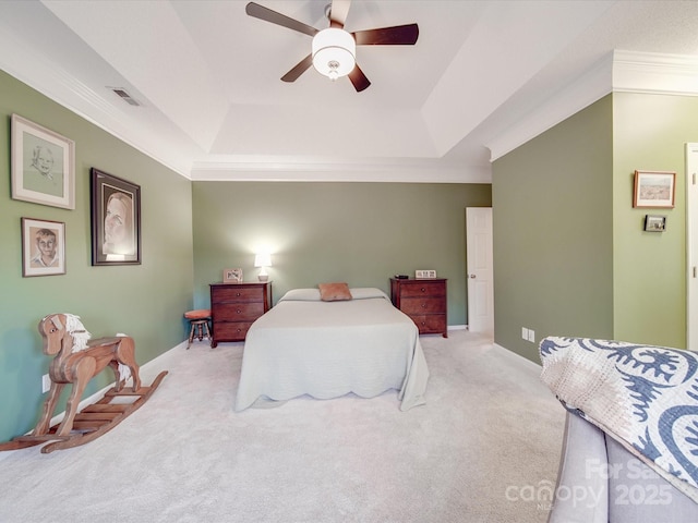 bedroom with a ceiling fan, a tray ceiling, light colored carpet, and visible vents