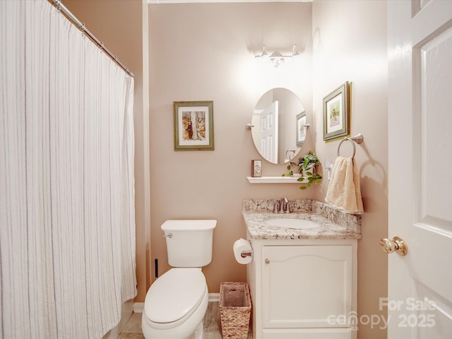 bathroom with baseboards, vanity, and toilet