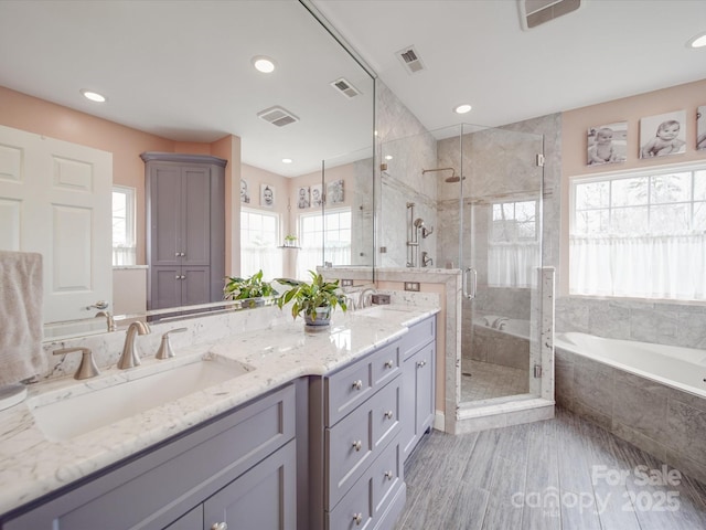 bathroom featuring a garden tub, visible vents, and a sink