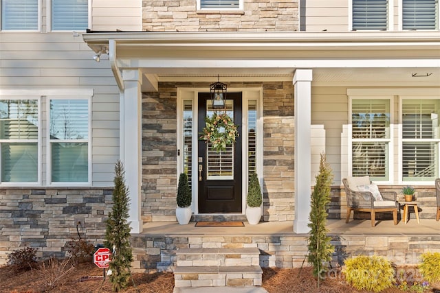 entrance to property with stone siding and a porch