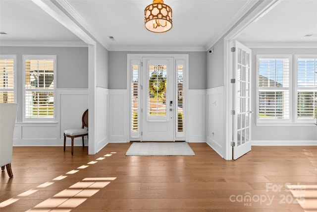 entrance foyer with a wainscoted wall, a healthy amount of sunlight, visible vents, and wood finished floors