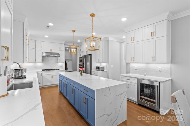 kitchen featuring wine cooler, blue cabinetry, appliances with stainless steel finishes, white cabinetry, and under cabinet range hood