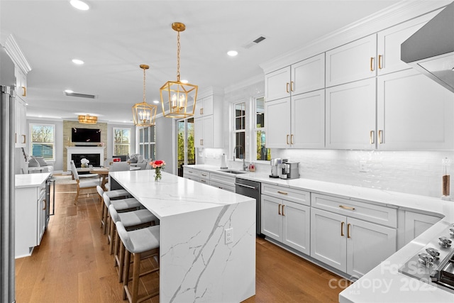 kitchen with tasteful backsplash, visible vents, a large fireplace, white cabinetry, and dishwasher