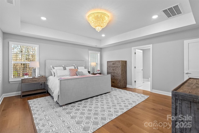 bedroom featuring visible vents, multiple windows, and wood finished floors