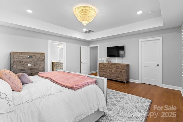 bedroom featuring recessed lighting, wood finished floors, visible vents, baseboards, and a raised ceiling