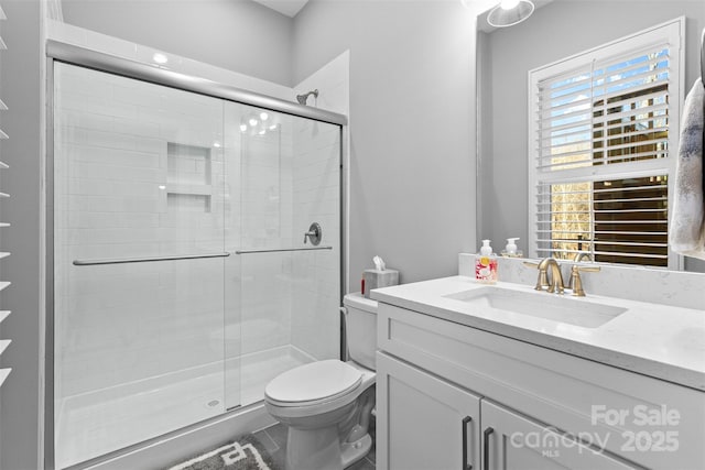 bathroom with a shower stall, toilet, and vanity