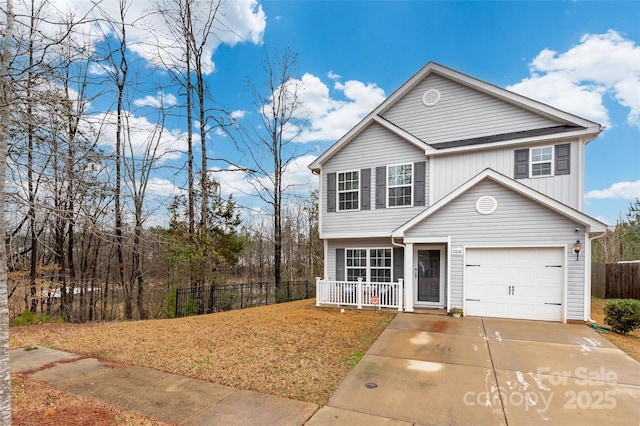 view of front facade featuring covered porch, driveway, fence, and a garage