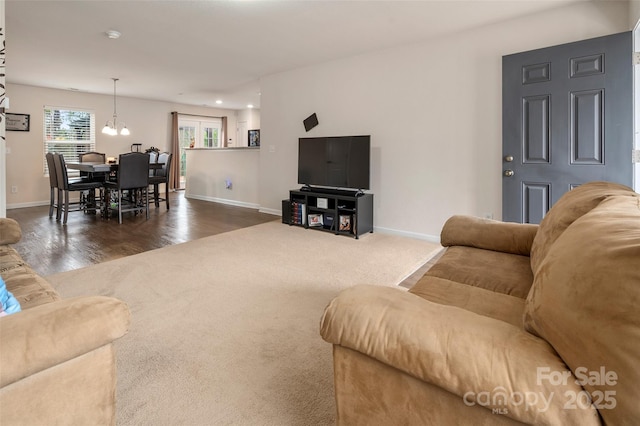 living area featuring dark colored carpet, dark wood-style flooring, and baseboards