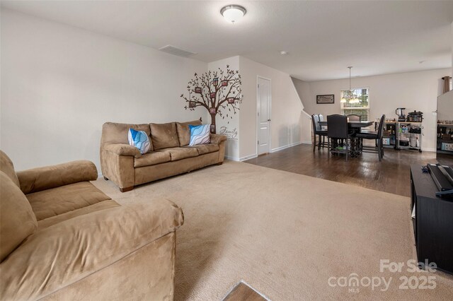 living room featuring dark wood-style flooring, dark carpet, visible vents, and baseboards