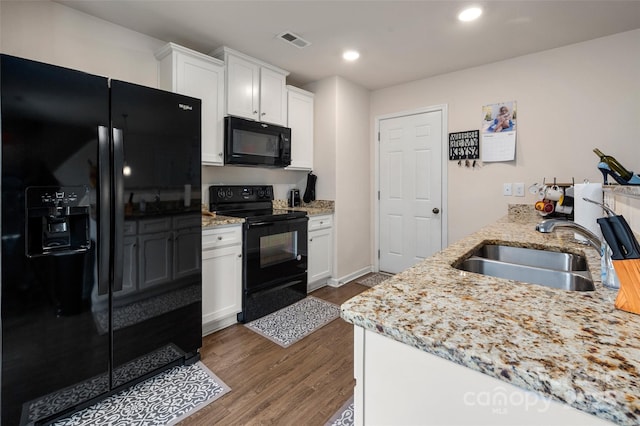 kitchen with black appliances, white cabinetry, visible vents, and a sink