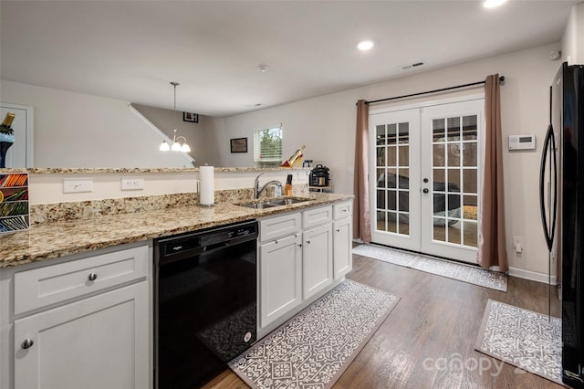 kitchen with decorative light fixtures, visible vents, white cabinets, a sink, and black appliances