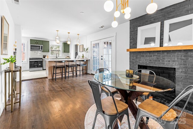 5825 Ruth Dr, Charlotte, NC 28215 - dining space with a fireplace, dark wood-type flooring, and french doors