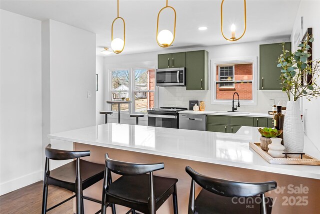 5825 Ruth Dr, Charlotte, NC 28215 - kitchen with a breakfast bar area, stainless steel appliances, a sink, green cabinets, and light countertops