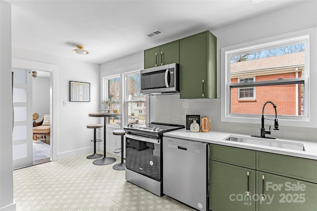 5825 Ruth Dr, Charlotte, NC 28215 - kitchen featuring stainless steel appliances, a sink, baseboards, light countertops, and green cabinetry
