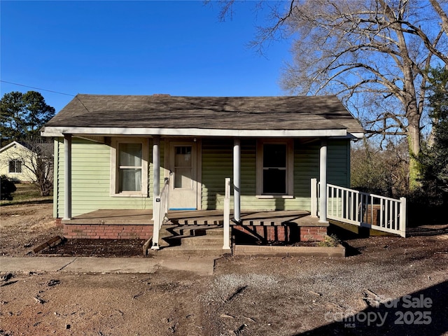 bungalow-style home featuring a porch and roof with shingles