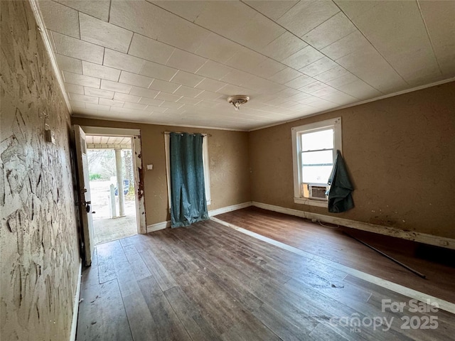 unfurnished room featuring baseboards, cooling unit, wood finished floors, and a healthy amount of sunlight