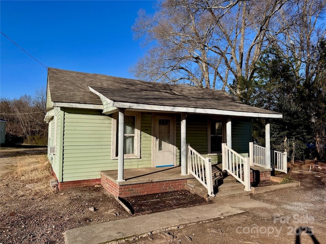 view of front of home featuring a shingled roof and covered porch