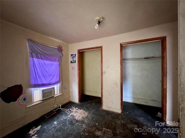 unfurnished bedroom with two closets, cooling unit, and visible vents