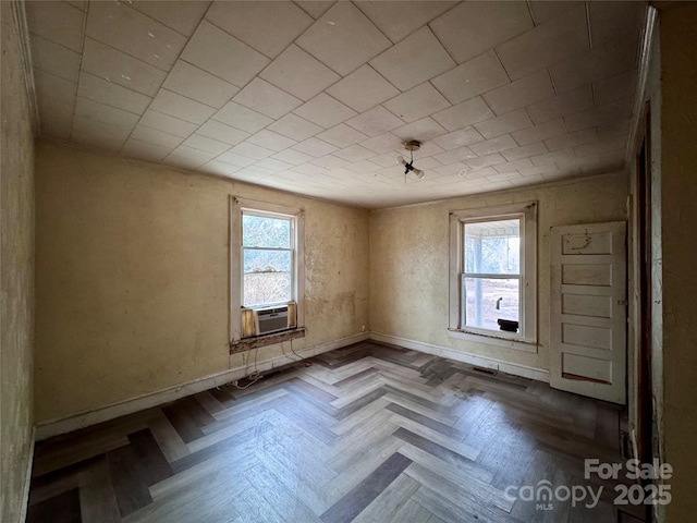 empty room featuring cooling unit, a healthy amount of sunlight, and baseboards