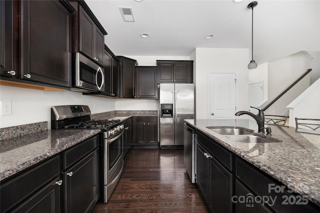 kitchen with a sink, hanging light fixtures, visible vents, stone counters, and stainless steel appliances