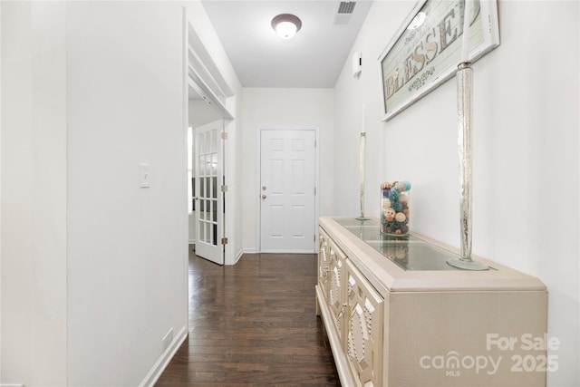 corridor featuring baseboards, visible vents, and dark wood-type flooring