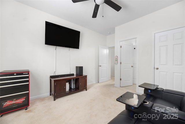 living area with ceiling fan, baseboards, and light colored carpet