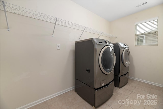 clothes washing area with visible vents, laundry area, baseboards, light tile patterned flooring, and separate washer and dryer