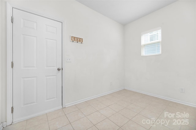 empty room with baseboards and light tile patterned floors