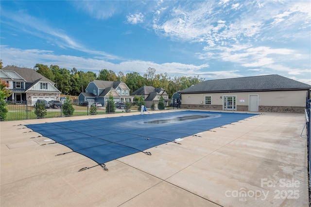 community pool featuring a patio, a residential view, french doors, and fence