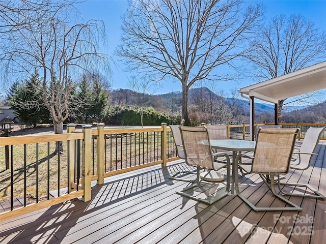 deck with outdoor dining space and a mountain view