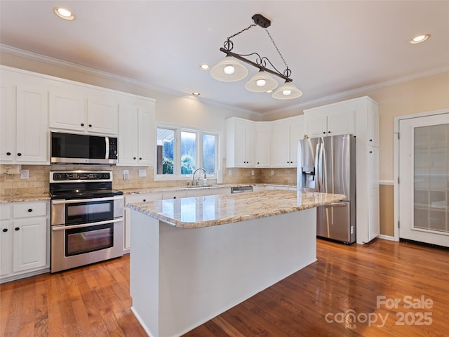 kitchen with white cabinetry, appliances with stainless steel finishes, crown molding, and wood finished floors