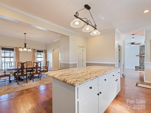 kitchen featuring light stone counters, light wood-type flooring, white cabinets, and arched walkways