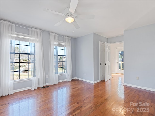 unfurnished room with a ceiling fan, baseboards, and hardwood / wood-style floors