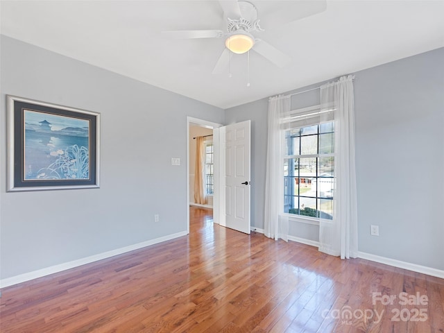 spare room with a ceiling fan, baseboards, and wood finished floors