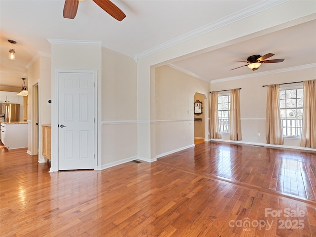 spare room with light wood-style floors, ornamental molding, baseboards, and a ceiling fan