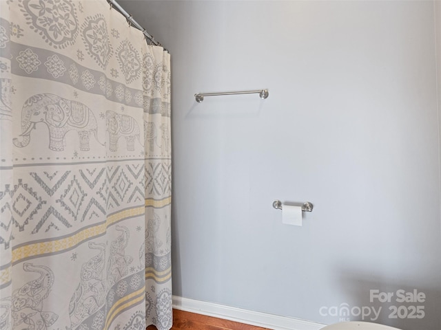 full bath with baseboards, wood finished floors, and a shower with shower curtain