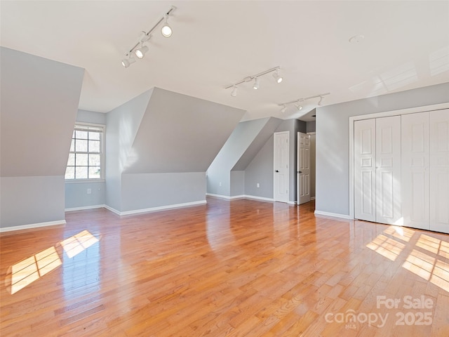 bonus room with light wood-type flooring, vaulted ceiling, and baseboards