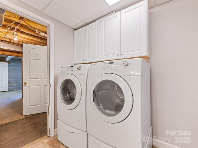 washroom featuring concrete block wall, cabinet space, separate washer and dryer, and light wood-style floors