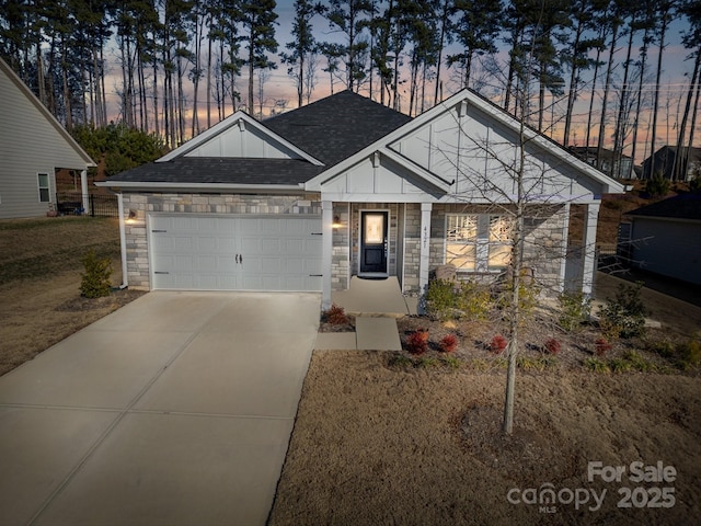 view of front of property with a garage, stone siding, a shingled roof, and concrete driveway