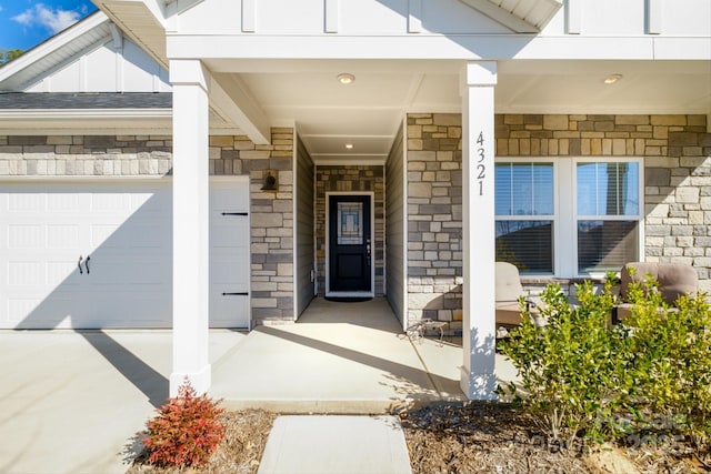 entrance to property with a garage, stone siding, and board and batten siding