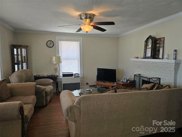 living area with dark wood-type flooring, a fireplace, a ceiling fan, and crown molding