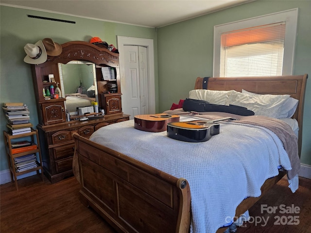 bedroom featuring dark wood-style floors, ornamental molding, and a closet